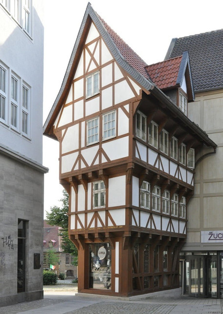 https://en.wikipedia.org/wiki/Upended_Sugarloaf

'The Upended Sugarloaf is a half-timbered house in the city of Hildesheim in the federal state of Lower Saxony in Germany.

It was built in the Middle Ages between 1500 and 1510. The shape of the building is unusual, looking similar to an upended sugarloaf. The ground floor is 17 m² in space, the first floor is larger and the second floor covers 29 m².

On 22 March 1945, in the Second World War, the building was destroyed by incendiary bombs.

Reconstruction was started on 27 October 2009. Many inhabitants of Hildesheim provided old photos and drawings for the project, as the original construction plans were not preserved. The building was inaugurated on 8 October 2010. The Upended Sugarloaf is now used as a café. The Association Altstadtgilde as building sponsor estimated that the total costs of the reconstruction amounted to €1,500,000.'