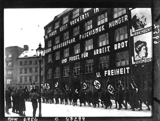 Nazis rally in front of the headquarters of the German Communist Party (KPD) in 1933 in Berlin. Slogans on the building include: Against war, fascism, hunger … for work, bread, and freedom. Robert Sennecke, Biblioteque nationale de France, Wikimedia Commons