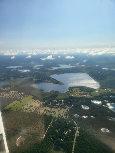 Several small lakes surrounded by agricultural fields and dotted above by small clouds.