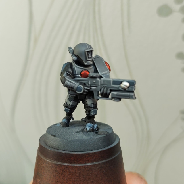 A plastic toy soldier, painted grey. Seen from the front.