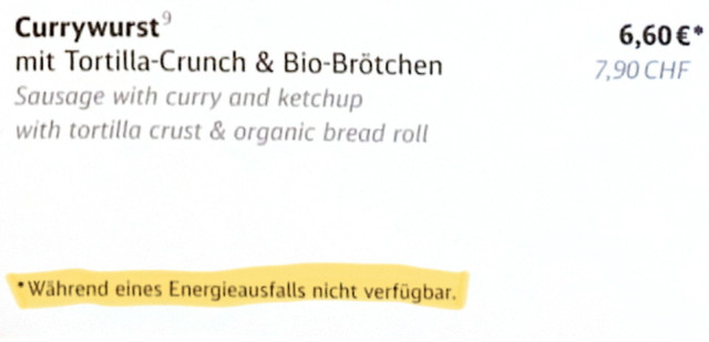 Ausschnitt aus der Not-Speisekarte im Zugrestaurant. Die Speisen sind deutsch und englisch beschrieben. Bei warmen Speisen ist als Fußnote am Preis angegeben: „Während eines Energieausfalls nicht verfügbar.“, allerdings nur bei der deutschen Beschreibung und nur in deutsch.

Der Rest des Textes ist 
„Currywurst® mit Tortilla-Crunch & Bio-Brötchen 6,60 €*
Sausage with curry and ketchup with tortilla crust & organic bread roll 7,90 CHF“