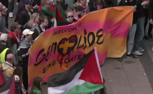 A huge banner that reads "Welcome to genocide song contest" with the swedish flag-heart in the center covered in blood