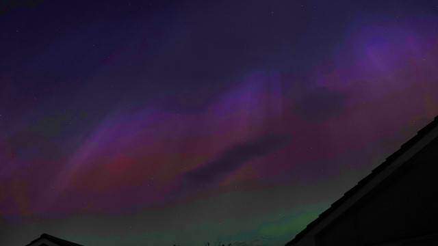 A photo of the night sky full of pink, purple, mauve, blue and green lighting from the aurora