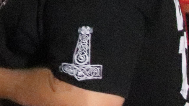 Schwarzes T-Shirt mit einem weissen Schwertgriff bedruckt.

Quelle:
https://www.belltower.news/thorshammer-mjoelnir-51332/