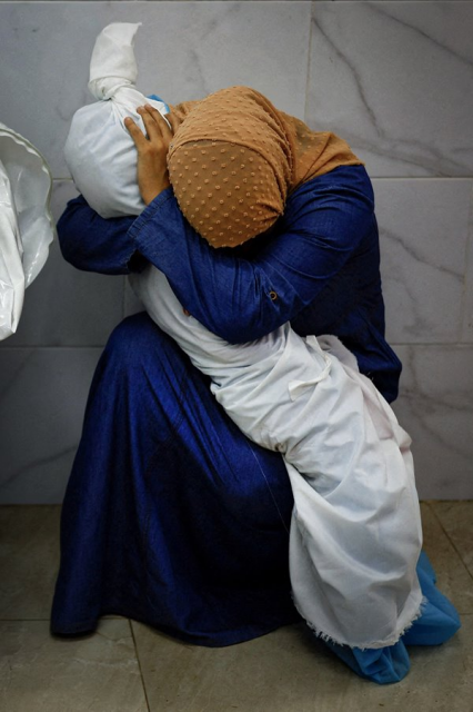 A woman in Gaza, in a blue dress wearing a yellow headscarf, crouched in a corner of a building. Her arms are wrapped around the dead, tiny body of a little girl wrapped in white cloth. The woman is covering her face in her own arms, mourning.

Additional context:

Inas Abu Maamar (36) cradling the body of her niece Saly (5) who was killed, along with her mother and sister, when an Israeli missile struck their home, in Khan Younis, Gaza.

Titled "A Palestinian Woman Embraces the Body of Her Niece", this photo by Mohammed Salem, Palestine, is the World Press Photo 2024.

https://www.worldpressphoto.org/news/2024/global-winners-announced