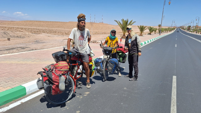 Pair of heavily loaded cycling nomads meet two solar cyclists in arid Morrocan landscape