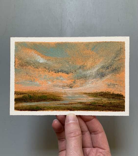 Photo of a hand holding an original marshland oil painting by Tisha Mark, "Marsh at Dusk" 4"x6" oil on Arches paper (2024). Painting of an early spring marsh with grasses in various greens and reddish tones, underneath a dusky orange-toned sky. There are cloud formations in various blues.