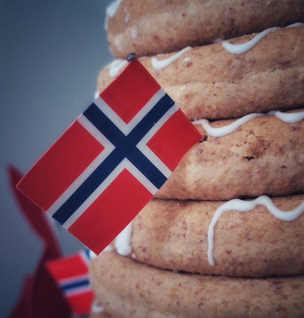 A psrt of a "kransekake" (a tower of rings made of almondflour and sugar) and a small norwegian flagg attached to it. This is a typical cake eaten at our constitution day.