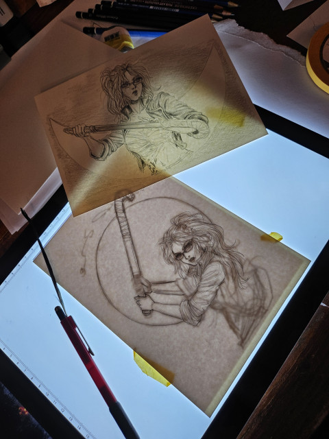 Two pencil illustrations on a lightbox, being worked on
