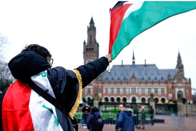 A man waves a Palestinian flag as people protest on the day of a public hearing held by The International Court of Justice (ICJ) to allow parties to give their views on the legal consequences of Israel's occupation of Palestinian territories before eventually issuing a non-binding legal opinion, in The Hague, Netherlands, February... 