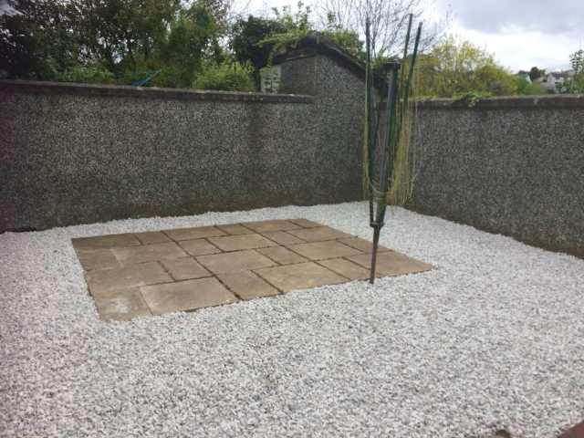 A bare garden with gravel and a patio.