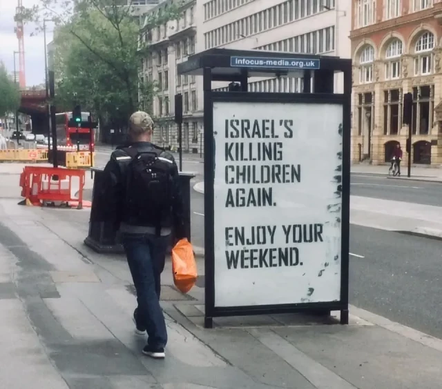 Poster on bus shelter (with man walking past looking) says:
"Israel's killing children again.
Enjoy your weekend".