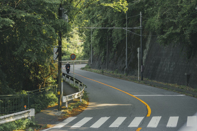 A rider riding a motorbike on a meandering, empty road.