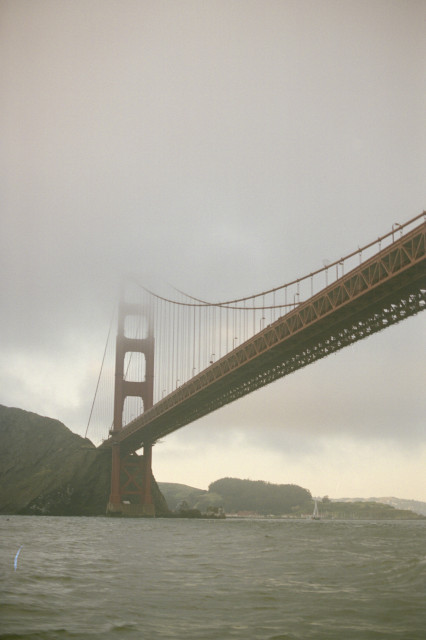 The Golden Gate Bridge viewed from below, the top consumed by a cloud.