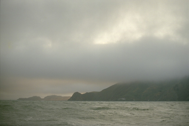 A green shore covered in low hanging clouds.