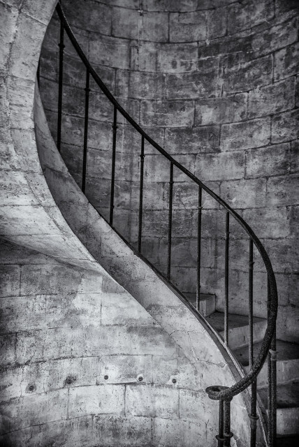 Spiral staircase made of stone with wrought iron handrail.