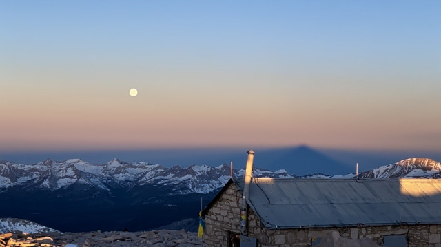 The full moon setting with the shadow of Mount Whitney casting on the horizon