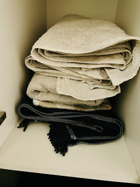 Cupboard shelf stacked with folded bath towels