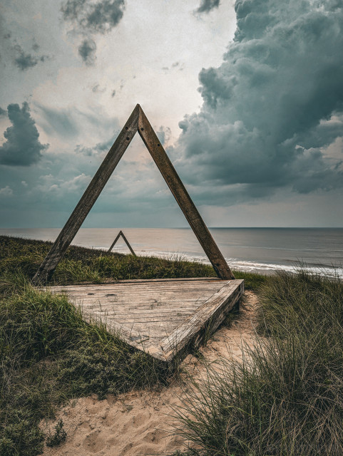 A viewing platform created by a series of wooden triangles overlooks the North Sea. The path on the outer row of dunes at Noordvoort was built to provide peace and quiet for seals and birds on the beach.