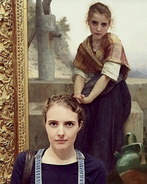 Individual, a woman, standing in front of portraits painted centuries ago where the likeness is strikingly scary. 