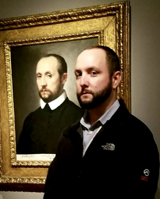 Individual, a man, standing in front of portraits painted centuries ago where the likeness is strikingly scary. 