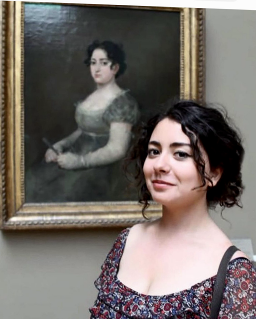 Individual, a young woman, standing in front of portraits painted centuries ago where the likeness is strikingly scary. 