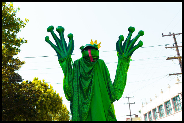 A costumed parade celebrant on stilts, dressed as a green tree frog with a gold crown and red tongue walks down a street and... need I go on? It's an ordinary day in San Francisco, ok?