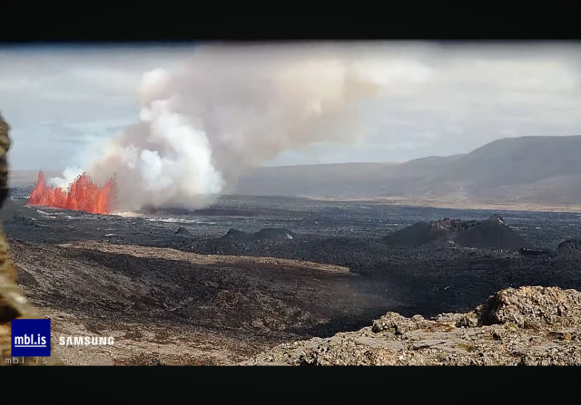 Screenshot from livestream. Huge lava fountains and lots of smoke are visible. To the right the old cone from the last eruption is visible. 