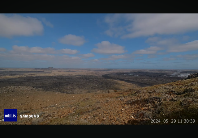 Screenshot from mbl livestream. A view over Svartsengi and on the road are several white busses and cars.