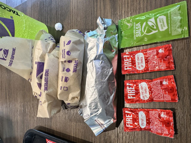 Three tacos, a burrito, a drink, three Fire sauce packets and an Avocado Verde Salsa packet.