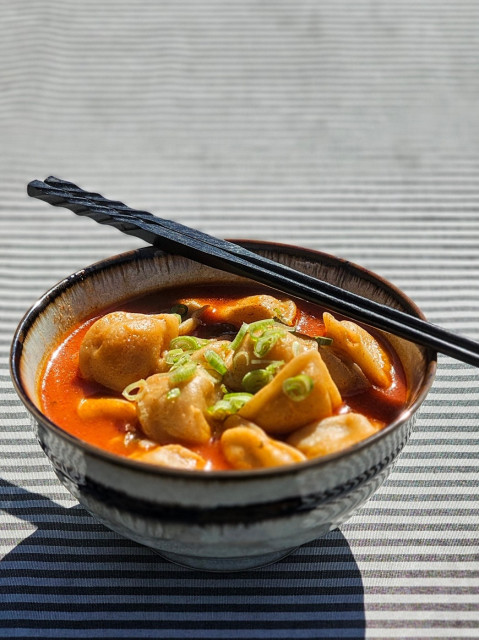 hjemmelavet koreansk mandu jeongol - spicy dumpling suppe  i skål med spisepinde på tværs.