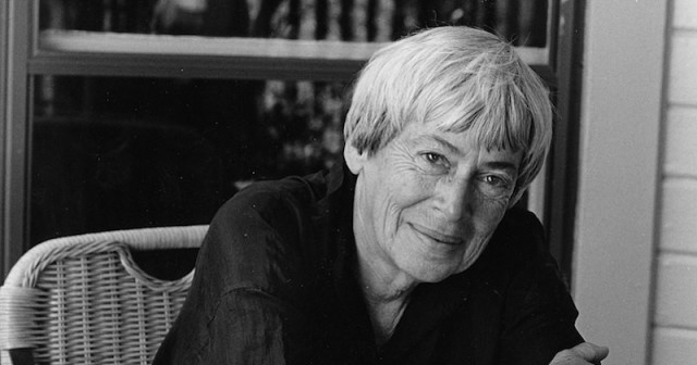 black and white photo of Ursula K. Le Guin, leaning forward and smiling