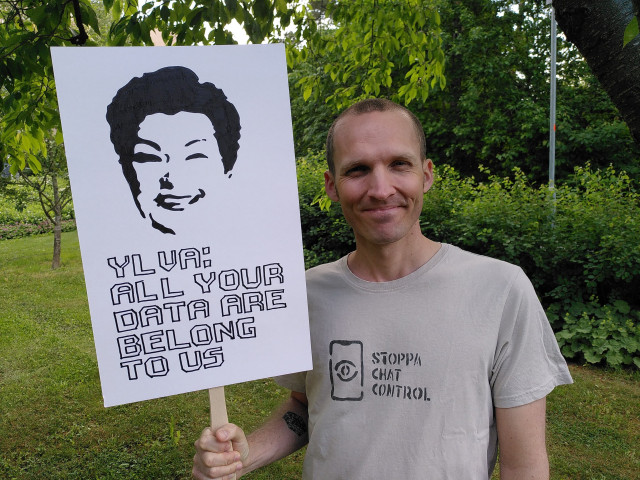 En bild på mig med en t-shirt där det står "Stoppa Chat Control" och ett plakat där det är konturerna för Ylva Johanssons ansikte med texten "Ylva: all your data are belong to us"