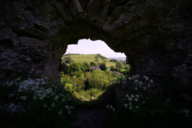 A glimpse of a scenic vista through a gap in an ancient stone wall.