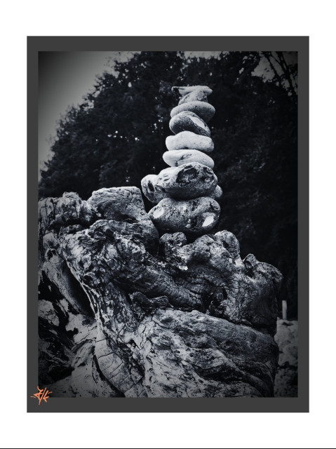 Schwarz-Weiß Foto von einem Steinturm auf einer angespülten Baumwurzel. Der Turm ist aus verschiedenen kleinen, für den Ostseestrand üblichen Steinen zusammengestellt.