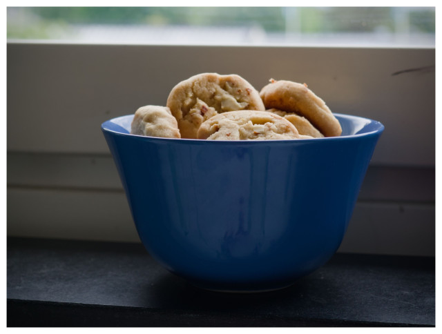 Cookies in a blue bowl standing on an interior window sill.