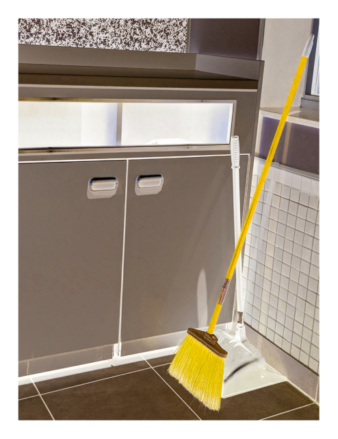inverted, recolored mcdonald's interior, daytime. a yellow broom leans against a tile half-wall with window above. two bins are housed a cabinet to the left. large tile floor.