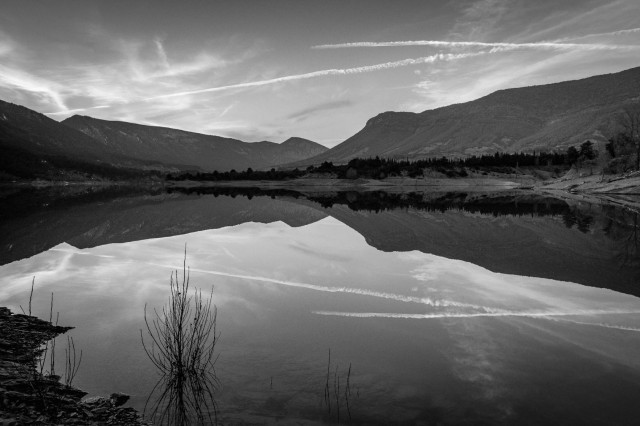 Fotografía en blanco y negro del embalse de Arguís a última hora de la tarde con reflejos del agua.