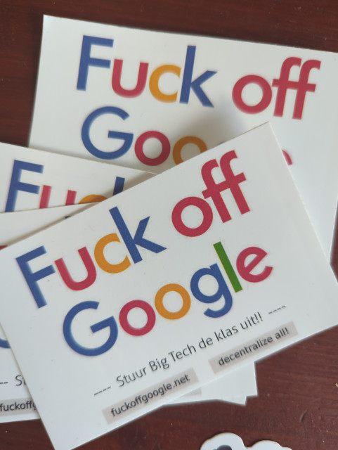 A bunch of stickers with the text "Fuck off Google" in the colorful house style font of Google. 

Small text "stuur BigTech de klas uit" (send BigTech out of the classroom)

and "fuckoffgoogle.net    decentralise all!"