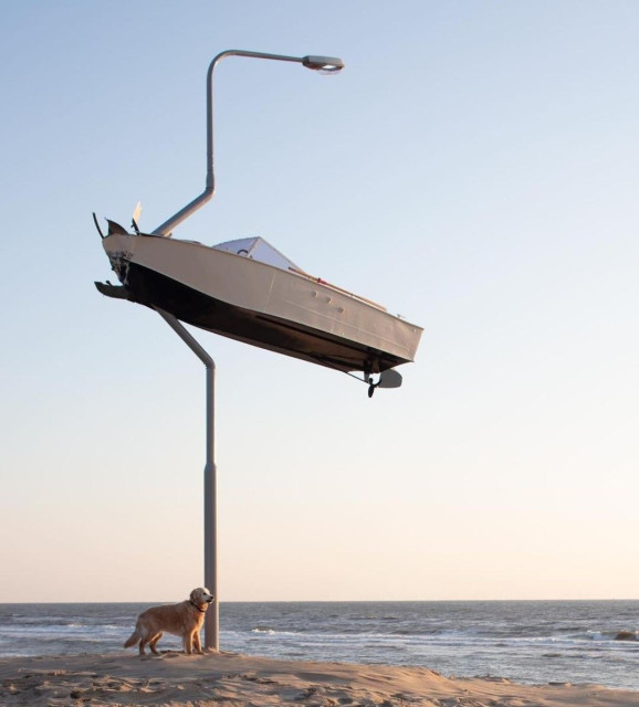 Urbanart. Art installation. The amusing installation of a speedboat was attached to a long pole with a street lamp. The lamppost makes two bends because a speedboat is hanging from it at a dizzying height. It was probably traveling too fast and crashed into the lamppost. In the photo, a dog is standing on the beach beneath the work of art and looking out to sea.
Info: Frankey aka Frank de Ruwe who
currently lives and works in Amsterdam. Where, if you look closely, you can discover his works in an unexpected places throughout the city. Street Art Zandvoort Festival will officially open on July 5.
