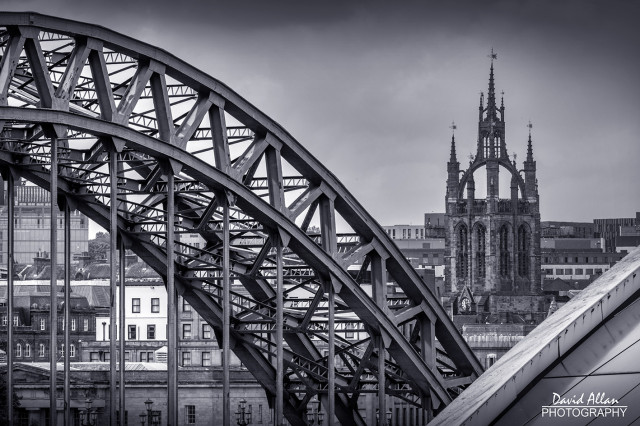 Newcastle's Tyne Bridge and the Glasshouse International Centre for music framing Newcastle Cathedral in a monochrome cityscape.