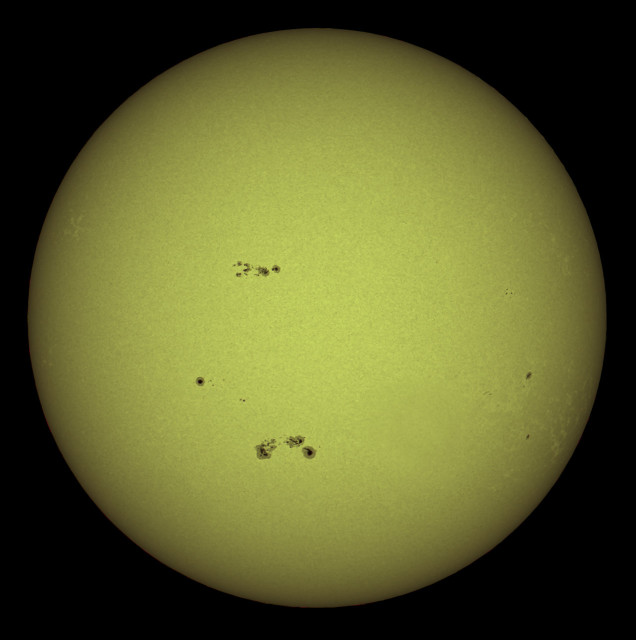 An image of the sun with visible dark sunspots scattered across its surface, presented against a black background.