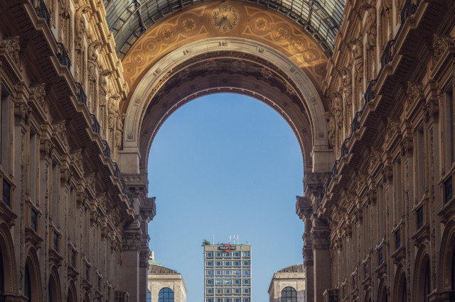 Fotografía de parte de la galería Vittorio Emanuele II de Milán con vistas a la salida por la plaza del Duomo y la luz del atardecer iluminando el interior.