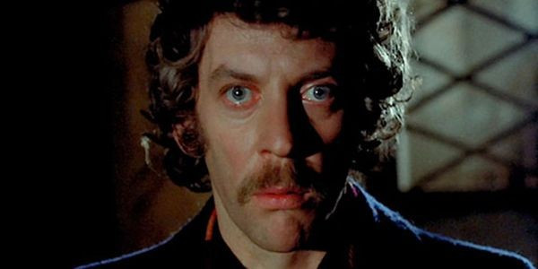 A still from the film Don't Look Now. A white man with blue eyes, curly brown hair and a moustache looks straight ahead as if in the grip of a sudden revelation.