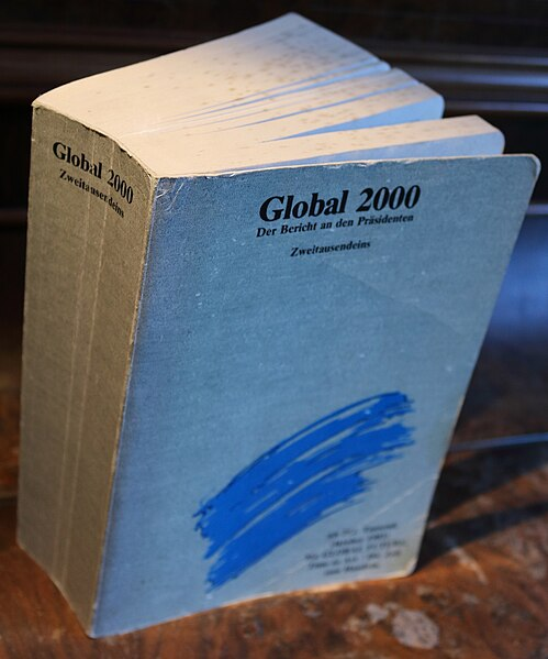 A very thick well-used grey paperback book with some blue stripes.

Above the stripes, the title "Global 2000"
"Der Bericht an den Präsidenten" (The report to the president)

