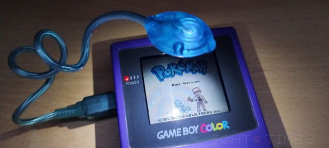 A Game Boy Color playing Pokémon Blue. There is a third party light that connects to a port in the console that provides a source of light, allowing you to play in the dark.