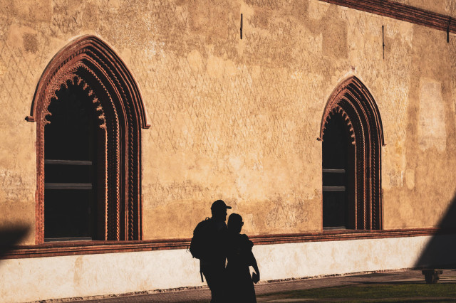 Fotografía donde se ve la silueta de una pareja paseando por dentro del recinto del castillo Sforza (Milán).