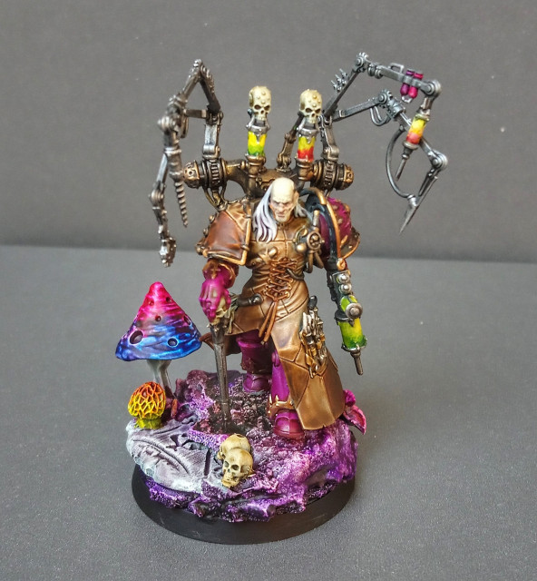 Painted miniature of Fabius Bile. He is walking over a rocky base (mostly painted in purple tones, but some are green/brown, too) with giant mushrooms and skulls. He is holding Torment and some kind of Injector. View from above. 