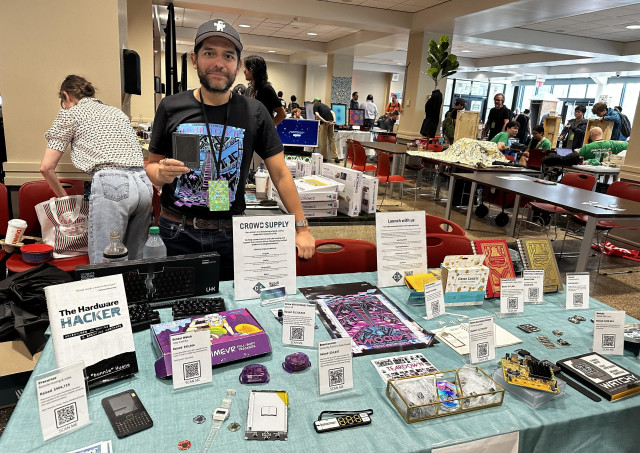 Photo of me standing behind a table full of Crowd Supply projects. 