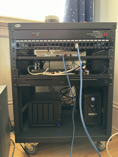 A black 12U rack with the various things described. There are only a few network cables visible from the front.